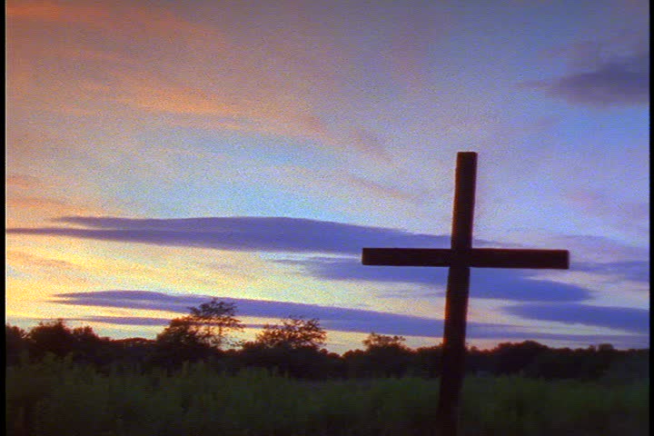 Cross burning on hill: MS wooden cross on hill outside at sunset. Blue and purple clouds.