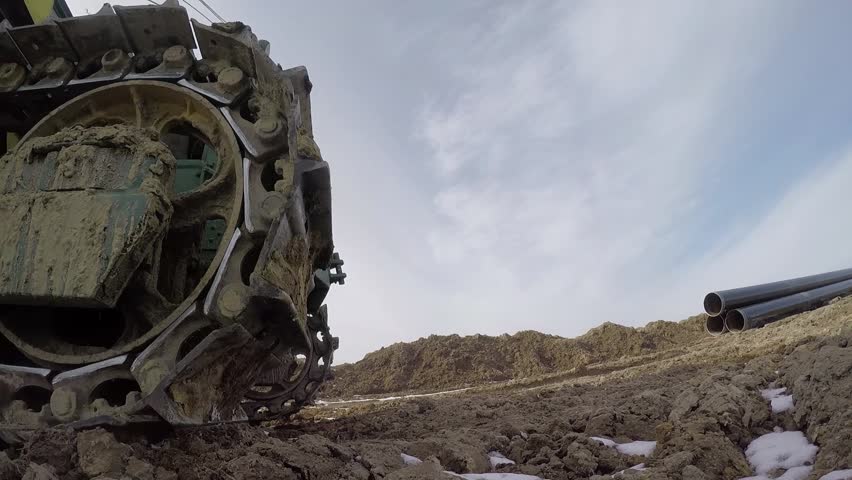 A close-up of the tracks of a bulldozer moving earth and snow. Construction works using special equipment.