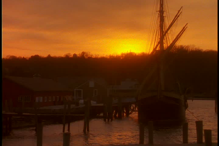 Exterior shots of seaport village in early morning light in Connecticut; WS seaport with ship in harbor in dark orange sunlight.