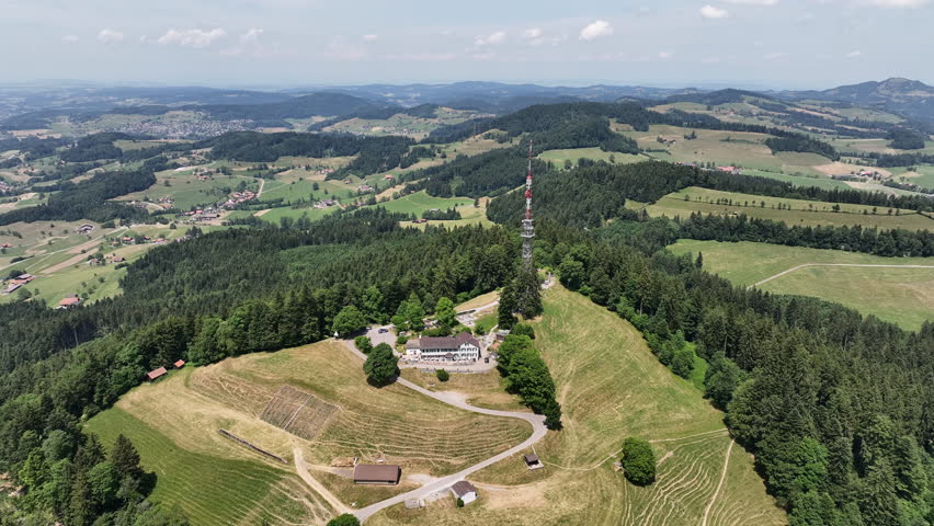Scenic aerial drone footage of the Bachtel Tower in the Zurich Oberland, Switzerland. Summer landscape with blue sky, mountains and panoramic views