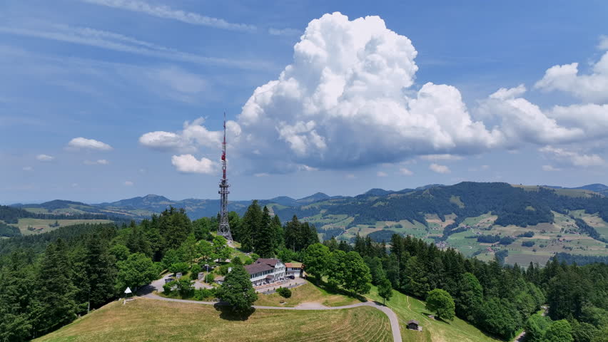 Scenic aerial drone footage of the Bachtel Tower in the Zurich Oberland, Switzerland. Summer landscape with blue sky, mountains and panoramic views