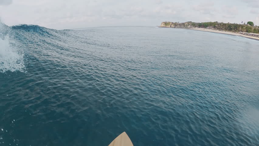 Surfer riding on perfect wave in ocean, first person view of surfing