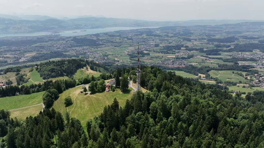 Scenic aerial drone footage of the Bachtel Tower in the Zurich Oberland, Switzerland. Summer landscape with blue sky, mountains and panoramic views
