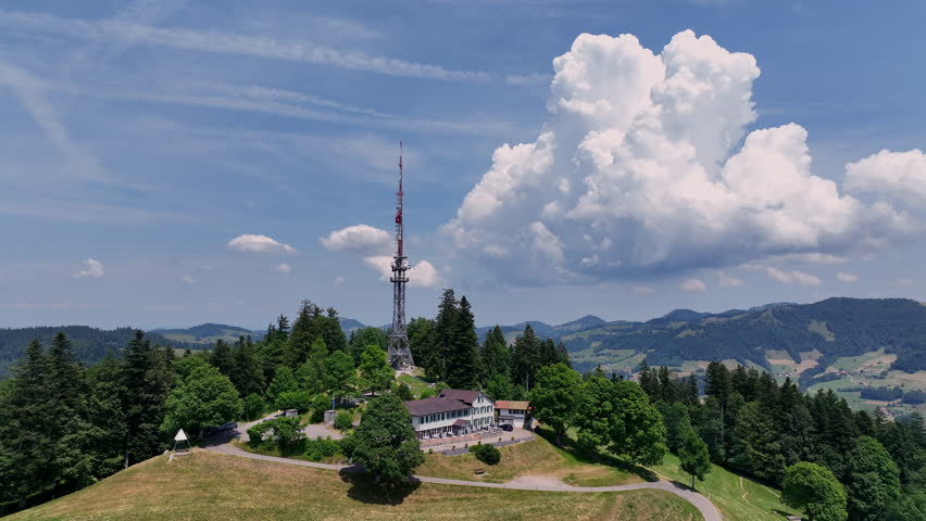 Scenic aerial drone footage of the Bachtel Tower in the Zurich Oberland, Switzerland. Summer landscape with blue sky, mountains and panoramic views