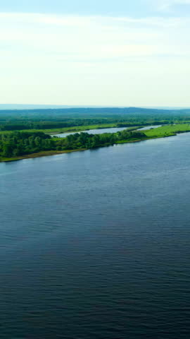 Wide river flows through green landscape under blue sky. Clip