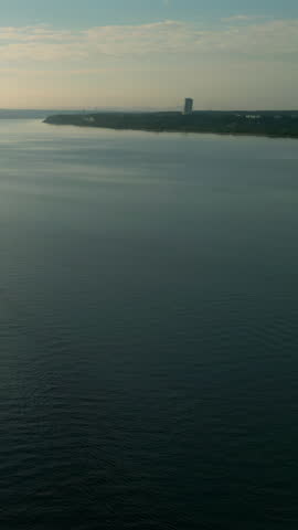 Wide river flows through green landscape under blue sky. Clip
