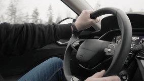 A man drives a modern car along a forest highway during a rainy autumn day. Close up of hands on a steering wheel inside a vehicle cabin during a long distance trip in bad weather conditions. - Powered by Shutterstock - Get 15% off with code: PIKWIZARD15