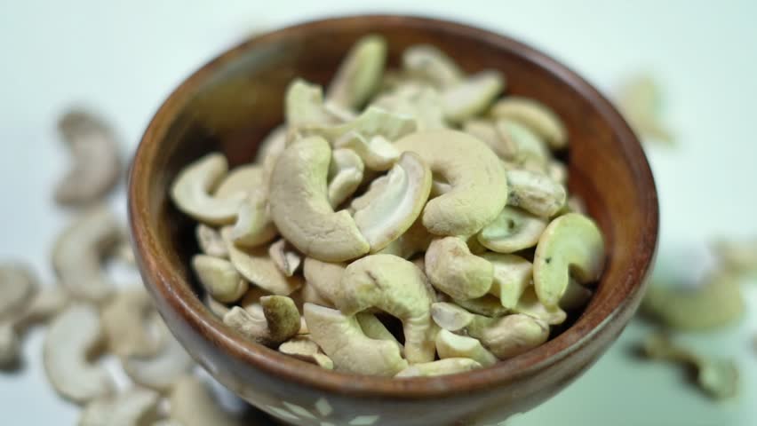 Cashew nuts rotating in a wooden bowl.