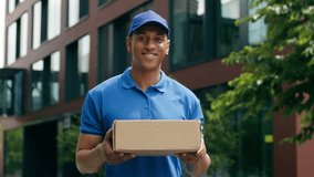 Happy smiling African American delivery man standing outdoors in city male courier holding package cardboard shopping order service looking at camera shipment joy postman professional worker handling - Powered by Shutterstock - Get 15% off with code: PIKWIZARD15