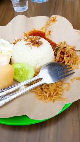 nasi uduk, Indonesian traditional breakfast made from coconut rice and spices, served with fried egg, noodles, peanuts, tempeh, crackers, cucumber, and chili sauce. closeup