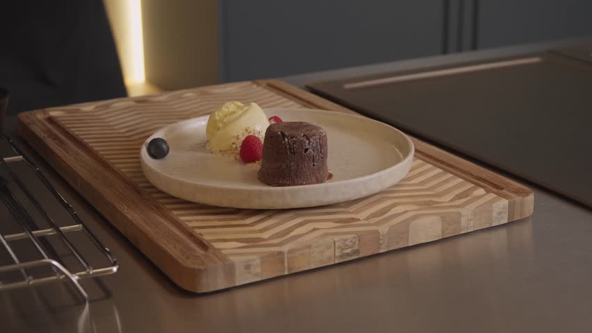 Chocolate lava cake with ice cream plated on board in kitchen