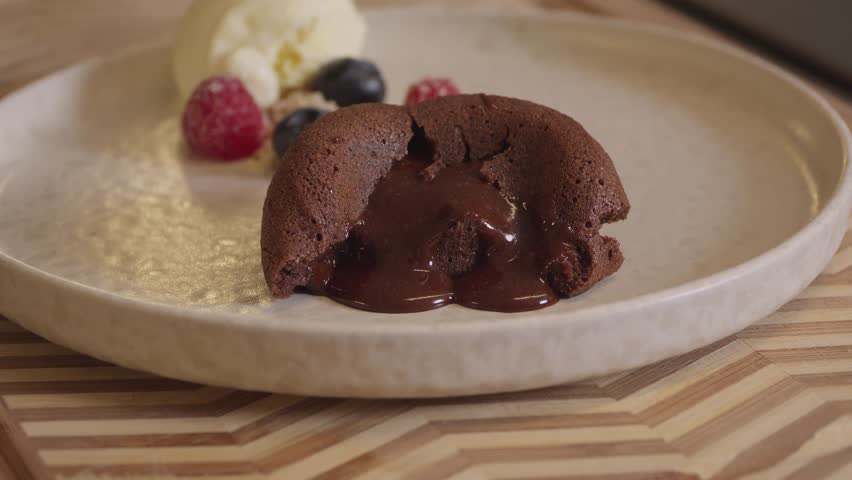 Baked chocolate cake releasing melted center served on plate
