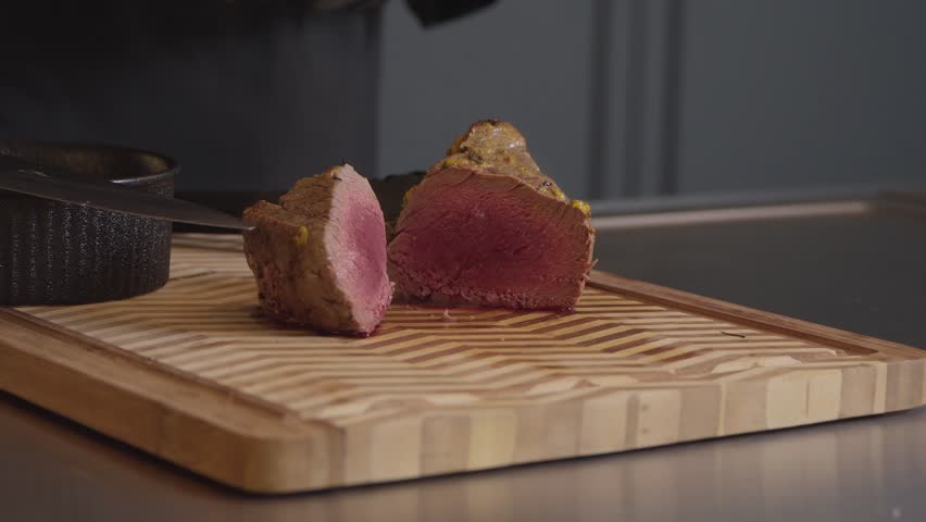 Cooked beef sliced on wooden board in kitchen