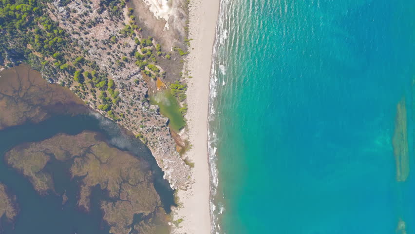 Dalyan, Turkey. Top down aerial drone view of Iztuzu Turtle Beach separating dark waters of Dalyan Strait from blue Mediterranean Sea with waves, golden sand spit. Aerial View