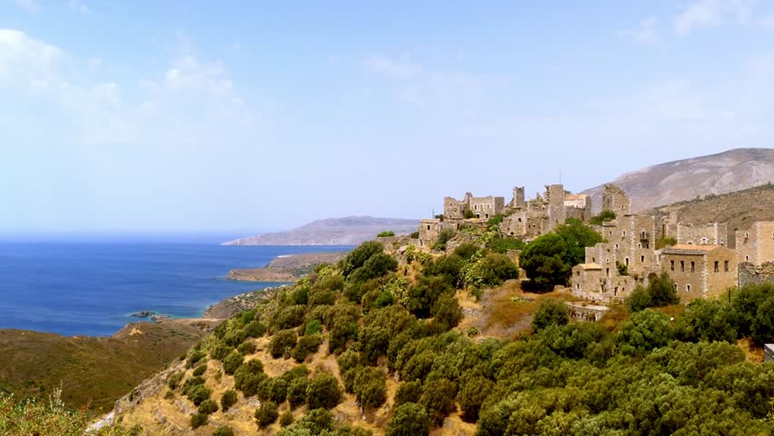 Historic stone village overlooking the Mediterranean Sea in Mani, Greece. Traditional coastal architecture and rugged landscape of the Peloponnese region under a bright summer sky