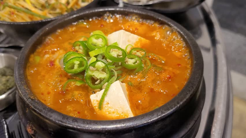 Spicy and Savory Korean Kimchi Jjigae Stew Boiling in a Ttukbaegi Earthenware Pot