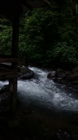 Clear river water flowing between rocks in a natural forest setting. Peaceful outdoor scene showing fresh water movement and a calm, relaxing atmosphere.