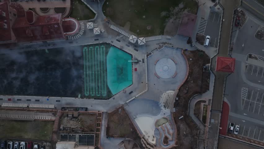 Aerial drone footage looking straight down over Glenwood Springs Colorado, showcasing streets and the hot springs area within the Colorado Rocky Mountains in daylight.