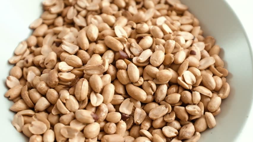 Closeup slow motion video of roasted clean peanuts. Healthy snack rich in nutrients. Natural light motion video of peanuts.