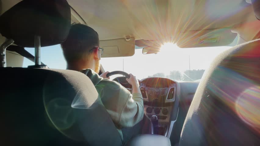 A man in a car. The sun is shining through the windshield. Slow motion.High quality 4k footage