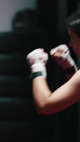 Young people practicing kickboxing banging a heavy sack in a dark gym