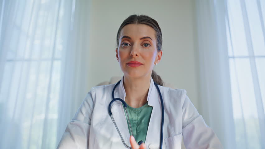 Medic consulting video meeting in medical clinic closeup pov view. Smiling physician lady giving healthcare advice by computer internet call. Professional woman doctor conducting online appointment