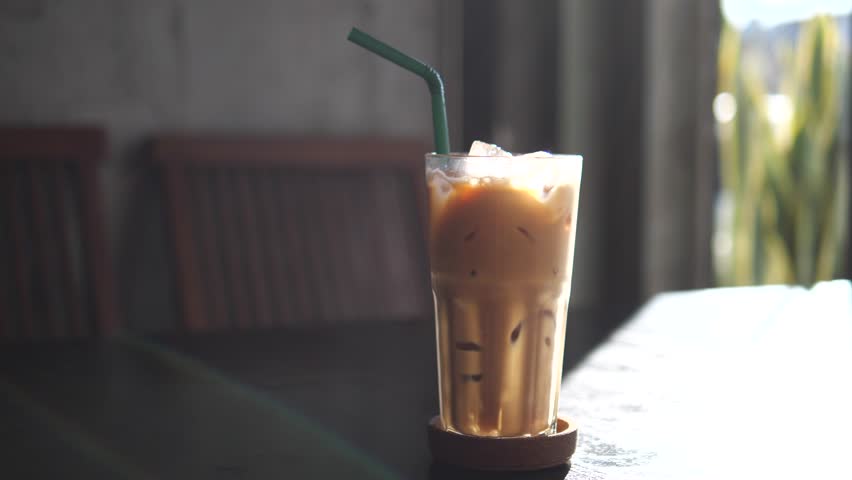 Iced Coffee in Glass with Straw on Table in Cozy Cafe with Soft Natural Light