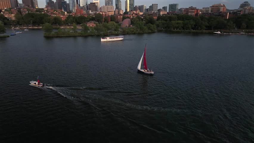 Aerial view of sailboats cutting through the river, contrasting with the skyline and the river