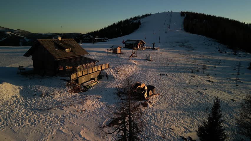 Wooden hut next to a ski slope - aerial footage at dusk