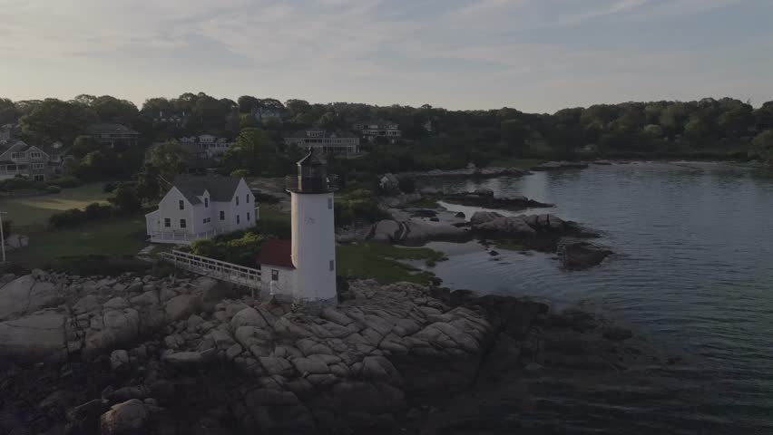 Aerial view of the lighthouse on the rocks surrounded by ocean and houses, contrasting with the sky, Gloucester, Massachusetts, United States.