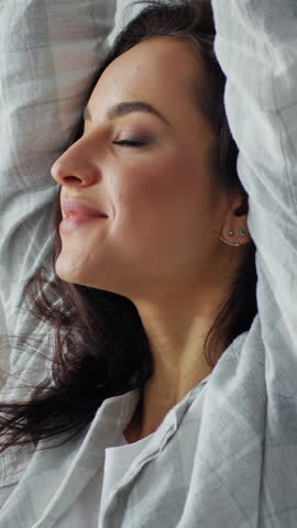 Close up Caucasian woman stretching arms touching neck pain discomfort tension back stretch move head yoga in bed in morning smiling carefree joyful girl female waking up in bedroom lady feeling good