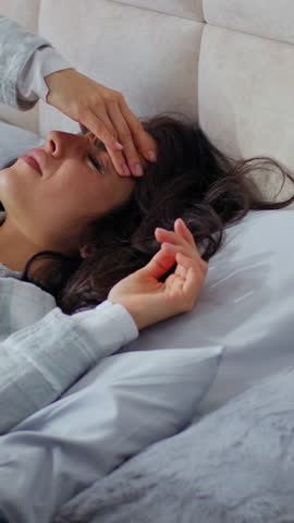 Unhealthy Caucasian woman waking up lying in bed holding head upset with headache pain symptom health difficulty female girl awaking migraine tension fever in bedroom home insomnia exhaustion tired
