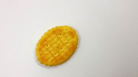 Single golden cheese flavored cracker rests diagonally upon a textured white surface highlighting its savory baked form and simple snack appeal. - Powered by Shutterstock - Get 15% off with code: PIKWIZARD15