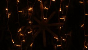 Festive 4K close-up of a bright white LED snowflake light ornament glowing softly against a dark background with warm orange string lights draped around for Christmas decoration, holiday lighting, - Powered by Shutterstock - Get 15% off with code: PIKWIZARD15