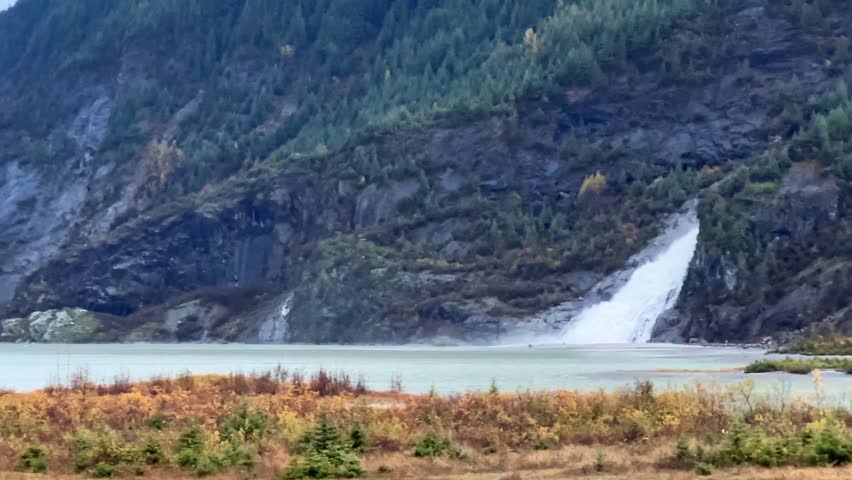Handheld telephoto shot panning from Nugget Falls to Mendenhall Glacier on a misty autumn day in Alaska