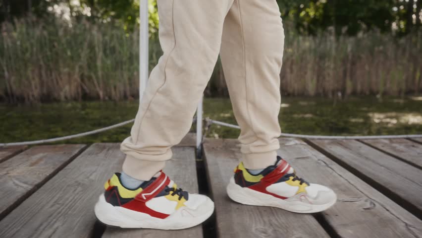 Close-up of sneakers stepping on pier boards outdoors. Emphasizes healthy movement, lifestyle balance and natural simplicity. High quality 4k footage