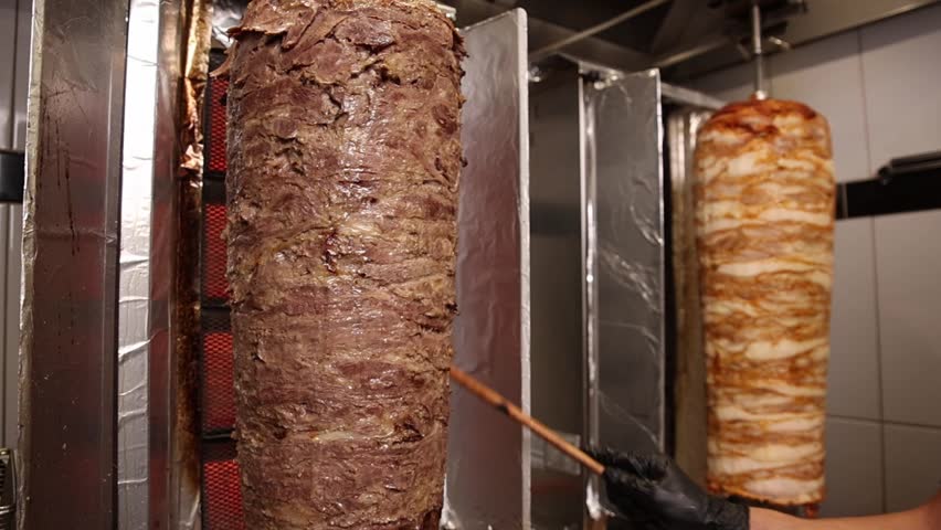 A chef makes shawarma in a café.  He fries meat.  Close-ups. 