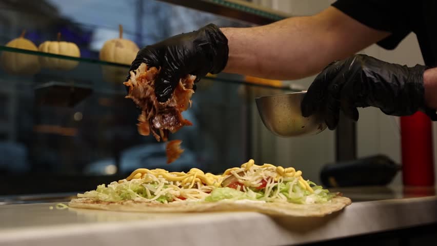 A chef makes shawarma in a café.  He fries meat.  Close-ups. 