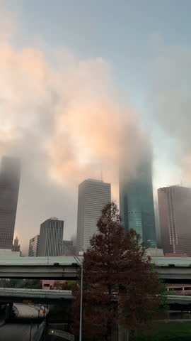 Real time video of fog drifting across the Houston Texas skyline at sunrise. Soft light and moving clouds interact with skyscrapers, creating a calm yet dynamic urban morning scene.