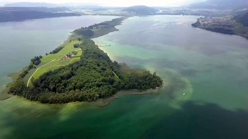 Aerial drone footage over Lake Biel in summer, featuring an island, a large passenger ship and surrounding lake scenery