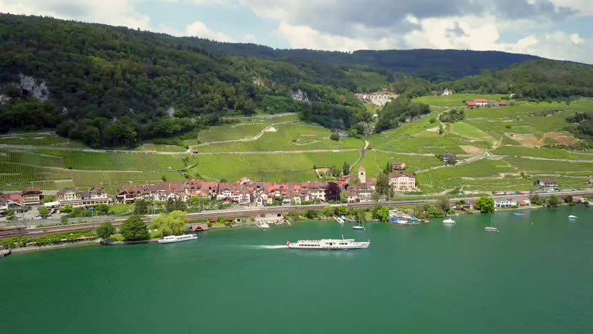 Aerial drone footage over Lake Biel in summer, featuring an island, a large passenger ship and surrounding lake scenery