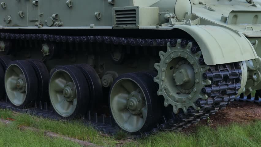 A large military tank sits atop a lush green grassy field, perfect for editorial or commercial use.