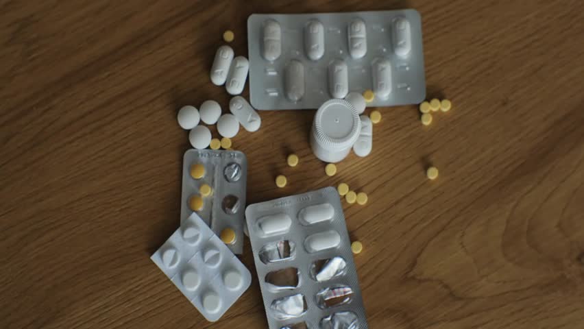 Top view of a hand sweeping pills off a table, symbolizing refusal of addiction, ideal for medical, health, and pharmaceutical projects.