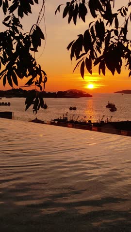 Beautiful tropical sunset over the sea with an infinity pool in the foreground. Scenic evening view in Kota Kinabalu, Borneo, Malaysia, featuring warm colors, calm water