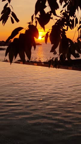 Beautiful tropical sunset over the sea with an infinity pool in the foreground. Scenic evening view in Kota Kinabalu, Borneo, Malaysia, featuring warm colors, calm water