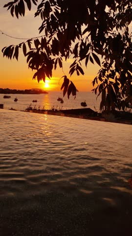 Beautiful tropical sunset over the sea with an infinity pool in the foreground. Scenic evening view in Kota Kinabalu, Borneo, Malaysia, featuring warm colors, calm water