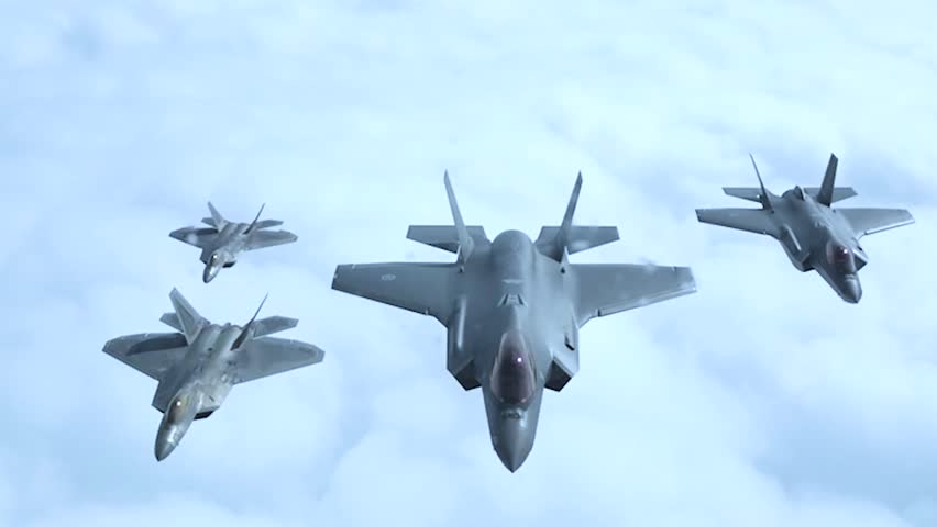 Four advanced stealth fighter jets F-35 fly in formation above clouds demonstrating coordinated airpower dominance.