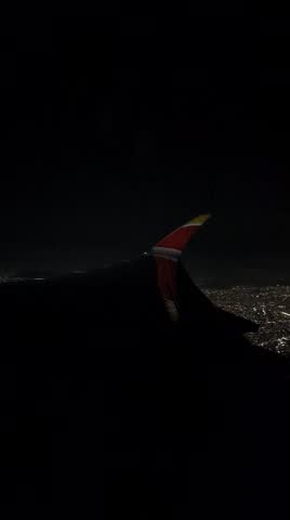 Night aerial view of Mexico City during airplane takeoff. City lights illuminate the urban landscape below while a jet engine of a large international aircraft is visible from the window. Editorial scene showing air travel, aviation industry, nighttime city, and international flight departure.