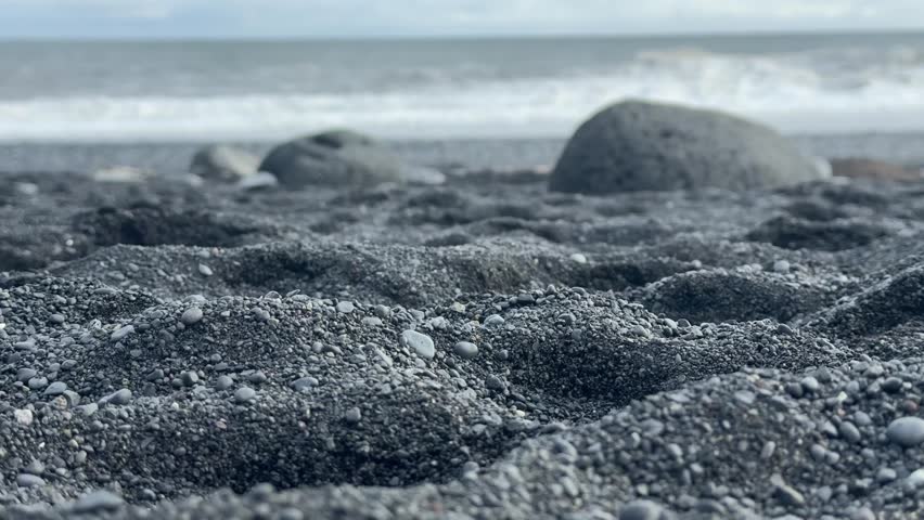 Dramatic Black Sand Beach with Scattered Rocks under Heavy Clouds. High quality FullHD footage