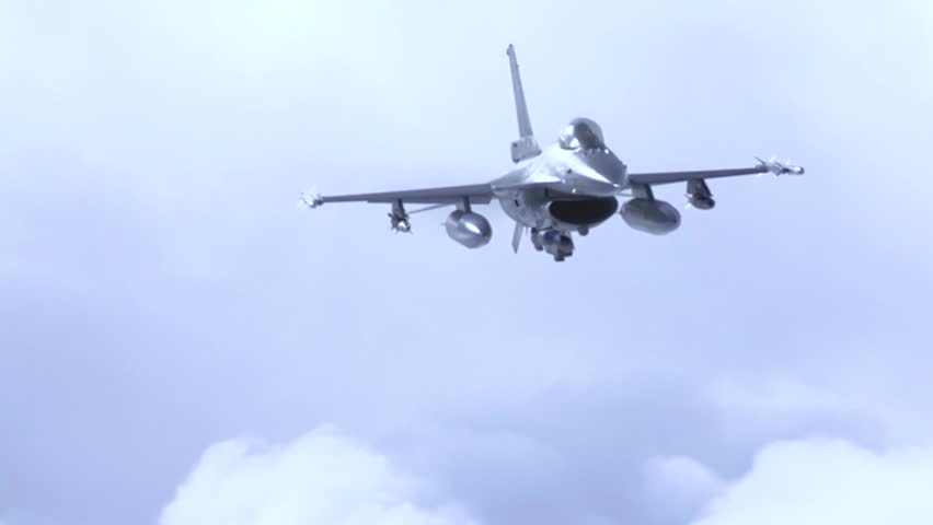 F-16 fighter approaches through towering clouds during high-altitude training sortie over open skies.